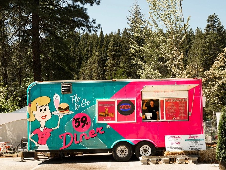 A colorful food truck parked among trees