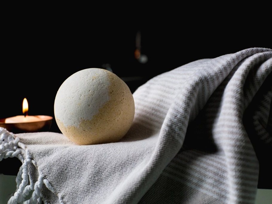 Folded spa towels with a candle and bath stone
